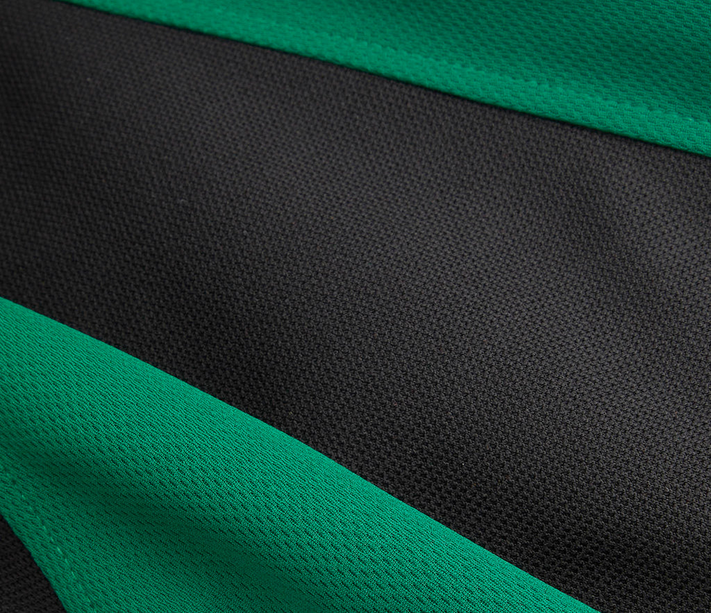 Close-up of the SPIRIT Fully Reversible Sports Top, showcasing its textured mesh fabric with green and black bands, small grandad collar, and contrast design.